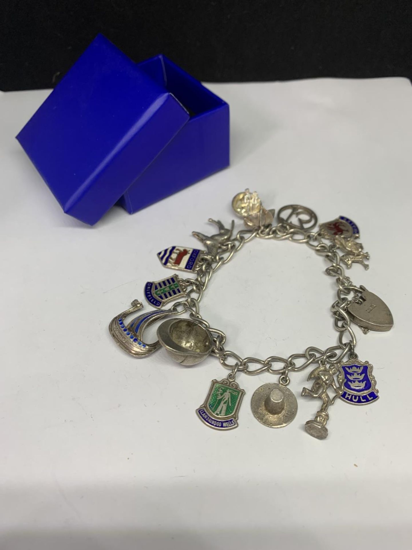 A SILVER CHARM BRACELET WITH THIRTEEN CHARMS TO INCLUDE A HORSE, RIDING HAT, DRAGON, APPLE ETC IN