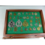 A GLAZED DISPLAY CASE CONTAINING THIRTY FIVE BRITISH MILITARY BADGES, 33CM X 49CM