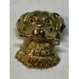 A SILVER GILT PENDANT IN THE FORM OF A DOGS HEAD WITH A STICK