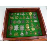 A GLAZED DISPLAY CASE CONTAINING THIRTY SIX BRITISH AND US MILITARY BADGES, 34CM X 40CM