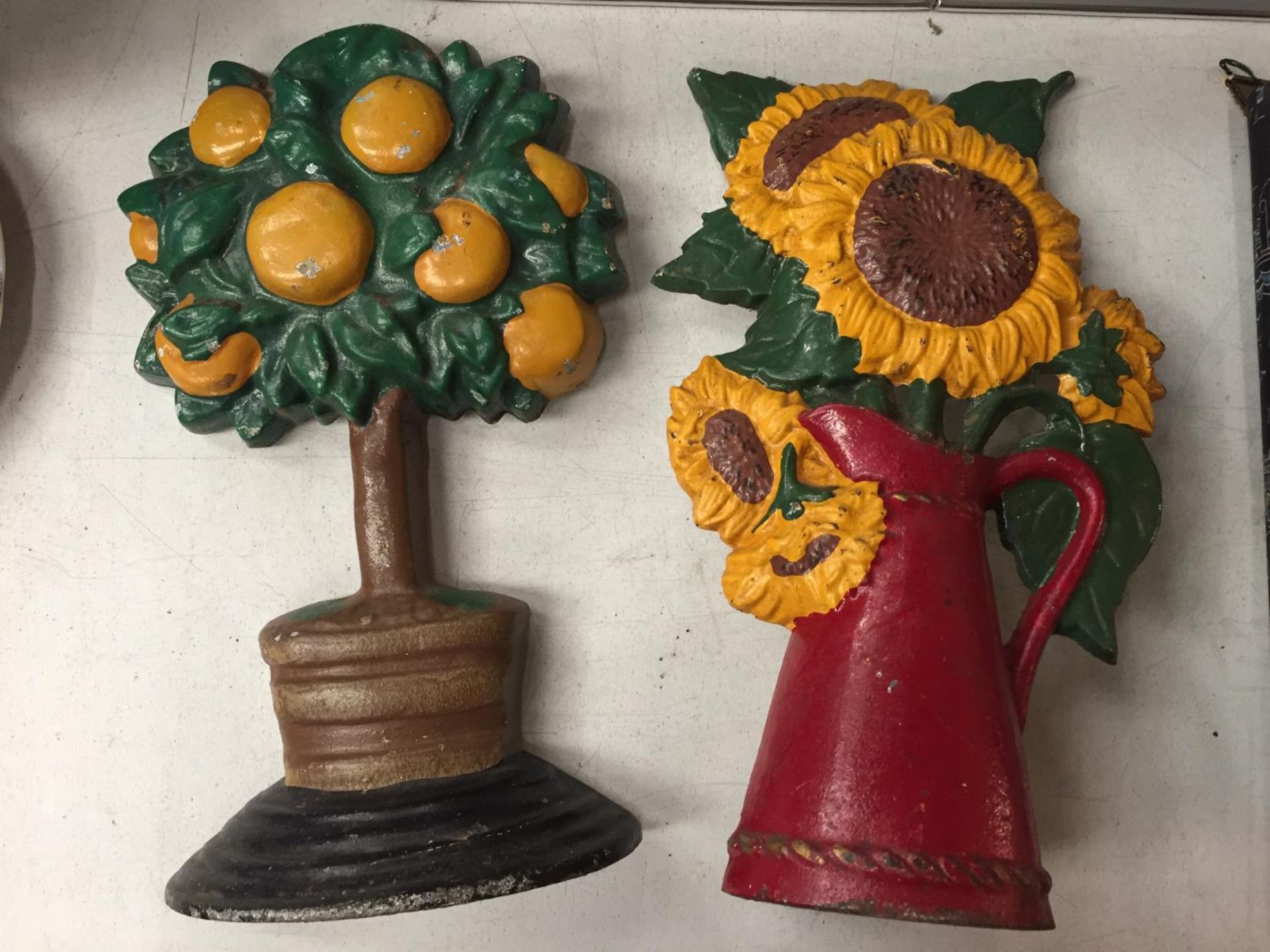 TWO CAST IRON DOOR STOPS TO INCLUDE AN ORANGE TREE AND A SUNFLOWER DESIGN