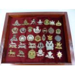 A GLAZED DISPLAY CASE CONTAINING THIRTY THREE BRITISH ARMY CAP BADGES, 35CM X 42CM