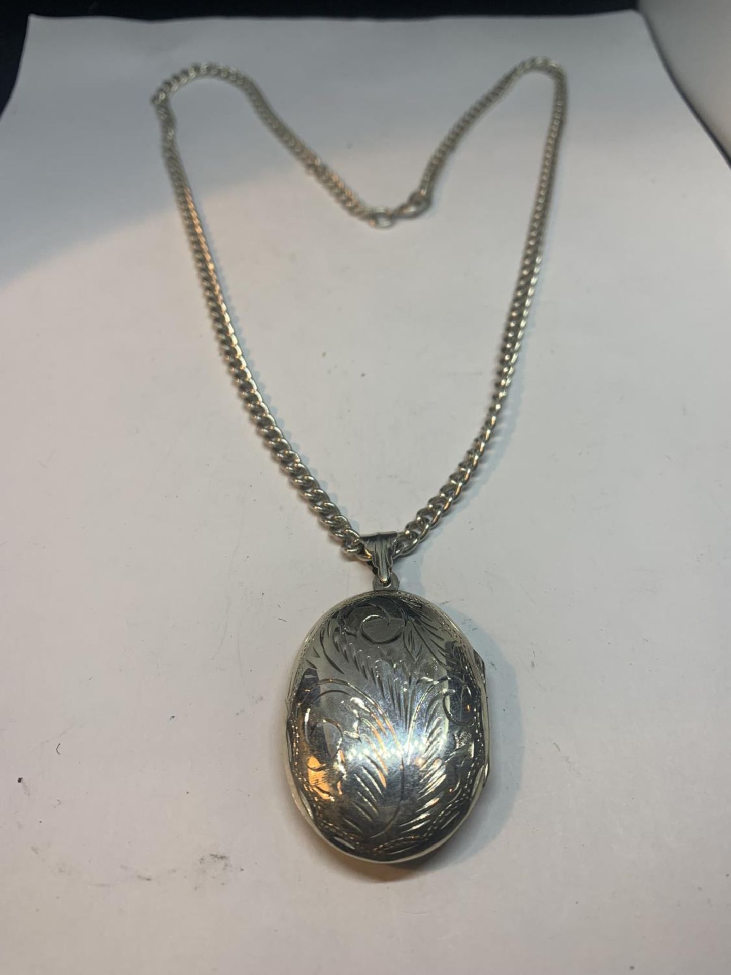 A SILVER NECKLACE WITH A LARGE OVAL LOCKET PENDANT