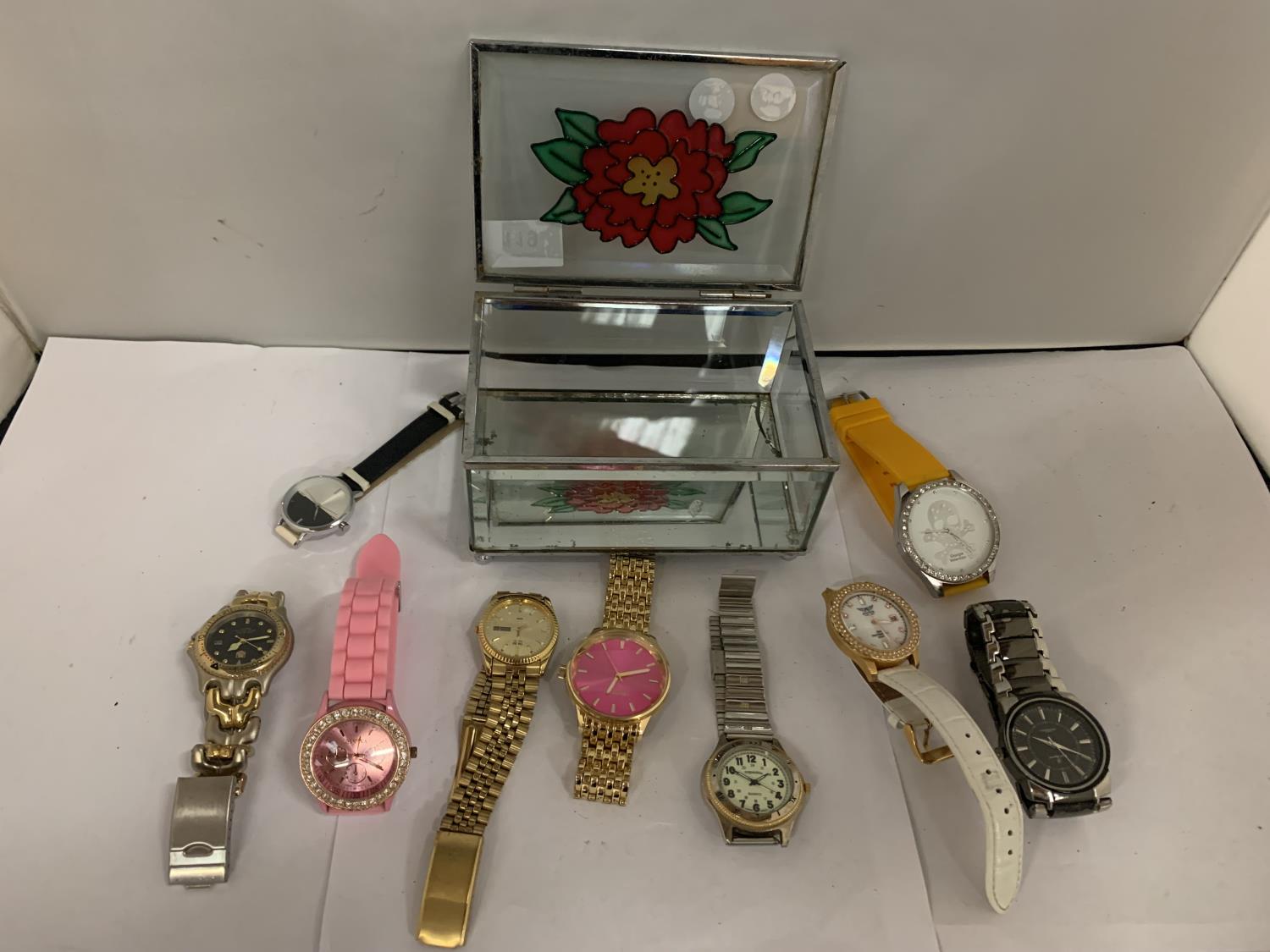 A DECORATIVE GLASS JEWELLERY BOX CONTAINING SEVERAL FASHION WATCHES