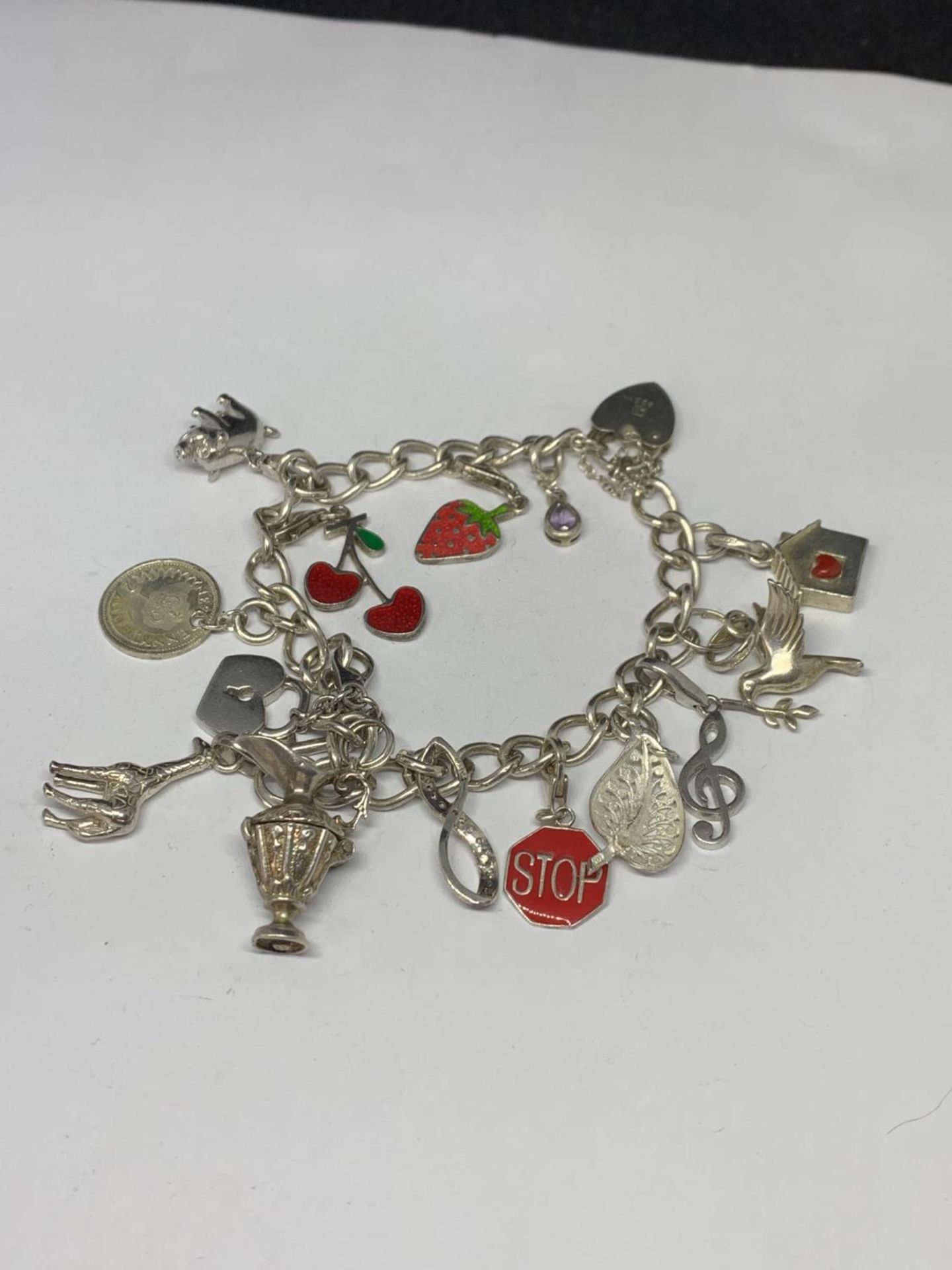 A HEAVY SILVER CHARM BRACELET WITH THIRTEEN CHARMS TO INCLUDE A STRAWBERRY, CHERRIES, DOVE ETC