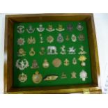 A GLAZED DISPLAY CASE CONTAINING THIRTY FIVE BRITISH ARMY BADGES, 34CM X 40CM