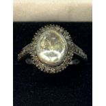 A CONTINENTAL WHITE AND YELLOW METAL RING WITH CENTRE DIAMOND AND SMALLER SURROUNDING DIAMONDS WHICH