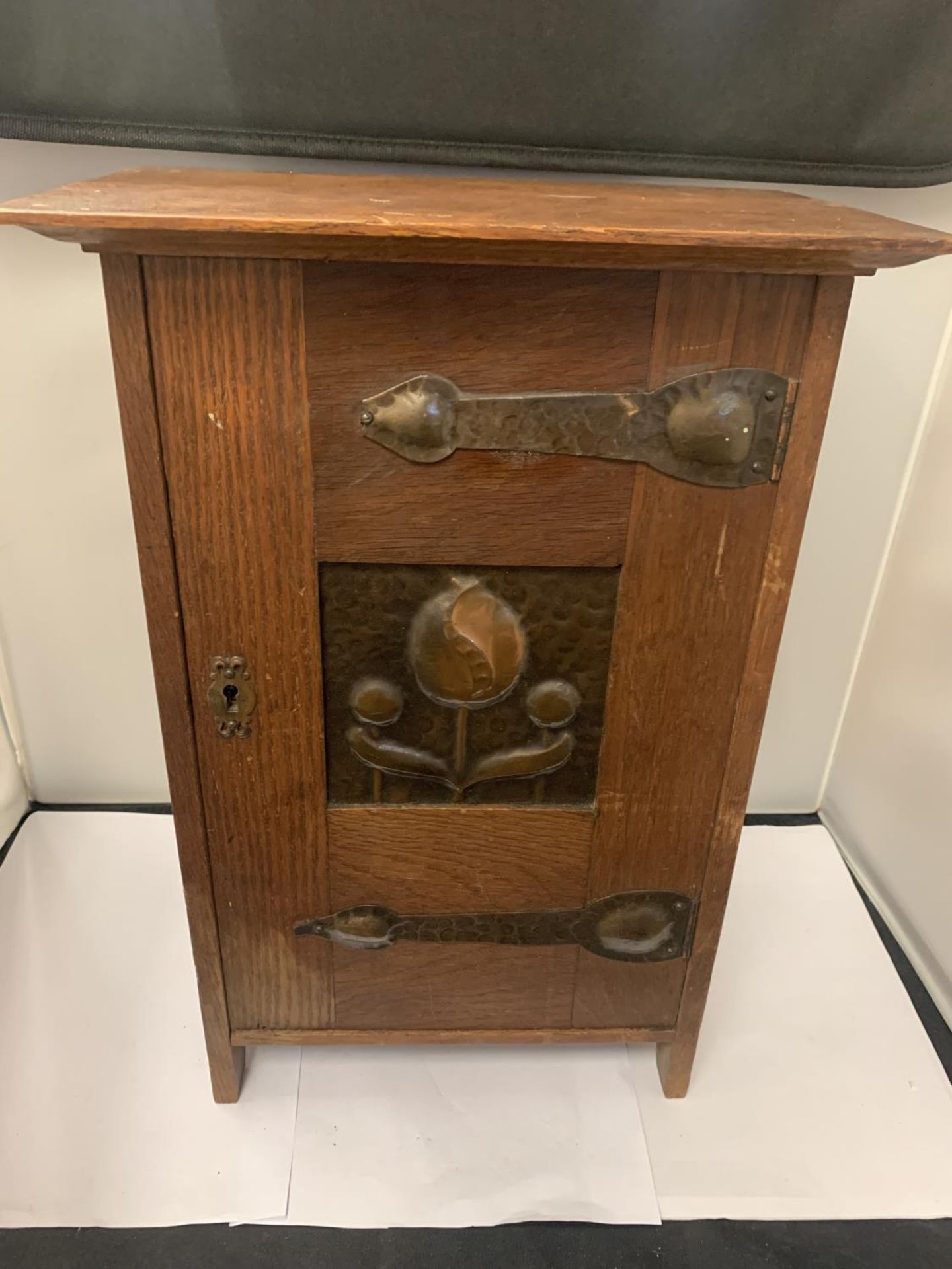 AN ARTS AND CRAFTS CABINET WITH COPPER HINGES AND DECORATIVE PANEL (LOCKED WITH NO KEY)