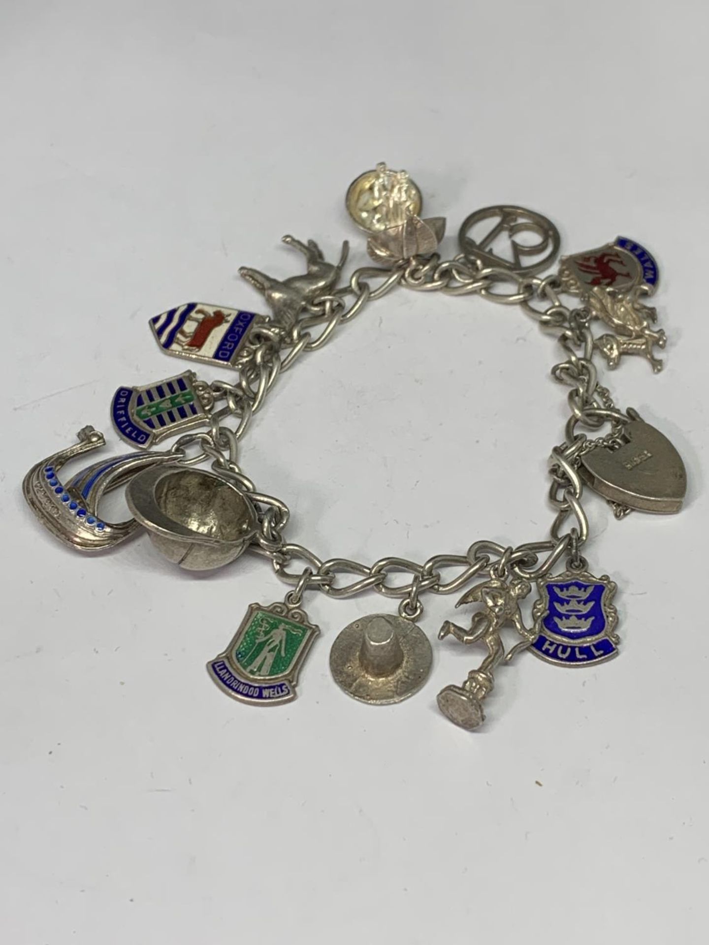 A SILVER CHARM BRACELET WITH THIRTEEN CHARMS TO INCLUDE A HORSE, RIDING HAT, DRAGON, APPLE ETC IN - Image 2 of 4