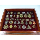 A GLAZED DISPLAY CASE CONTAINING THIRTY SIX BRITISH ARMY CAP BADGES, 32CM X 43CM