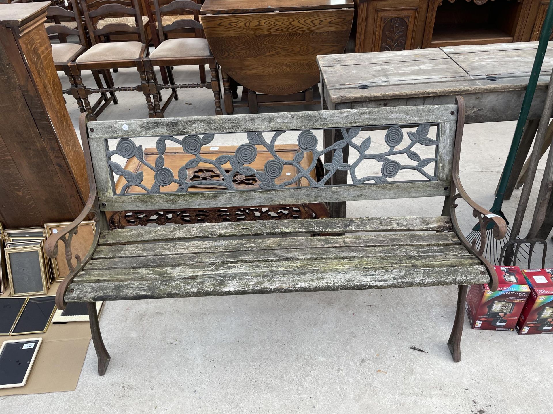 A WOODEN SLATTED GARDEN BENCH WITH CAST ENDS AND BACK