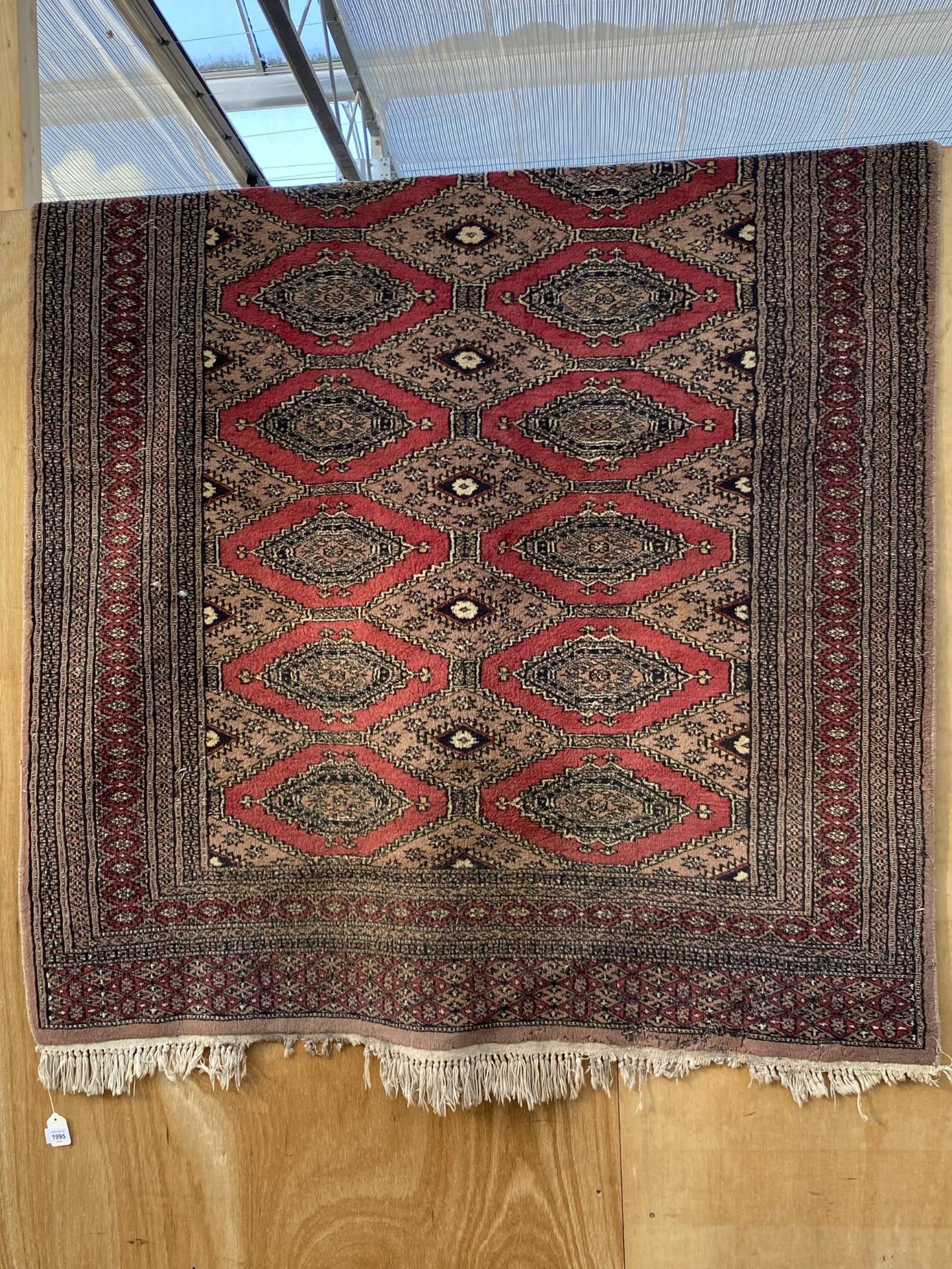 A RED PATTERNED FRINGED RUG