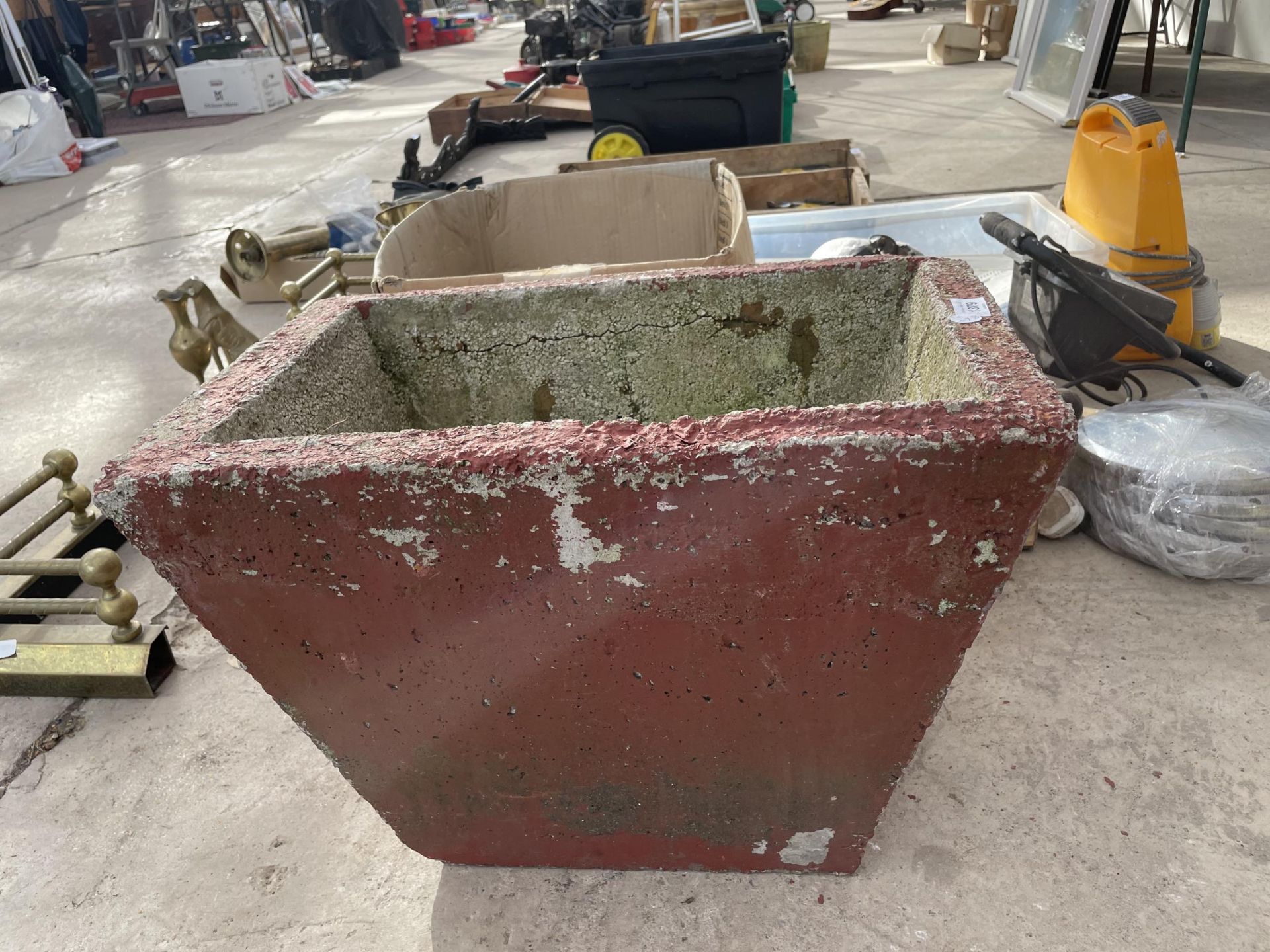 A RED PAINTED CONCERETE PLANTER