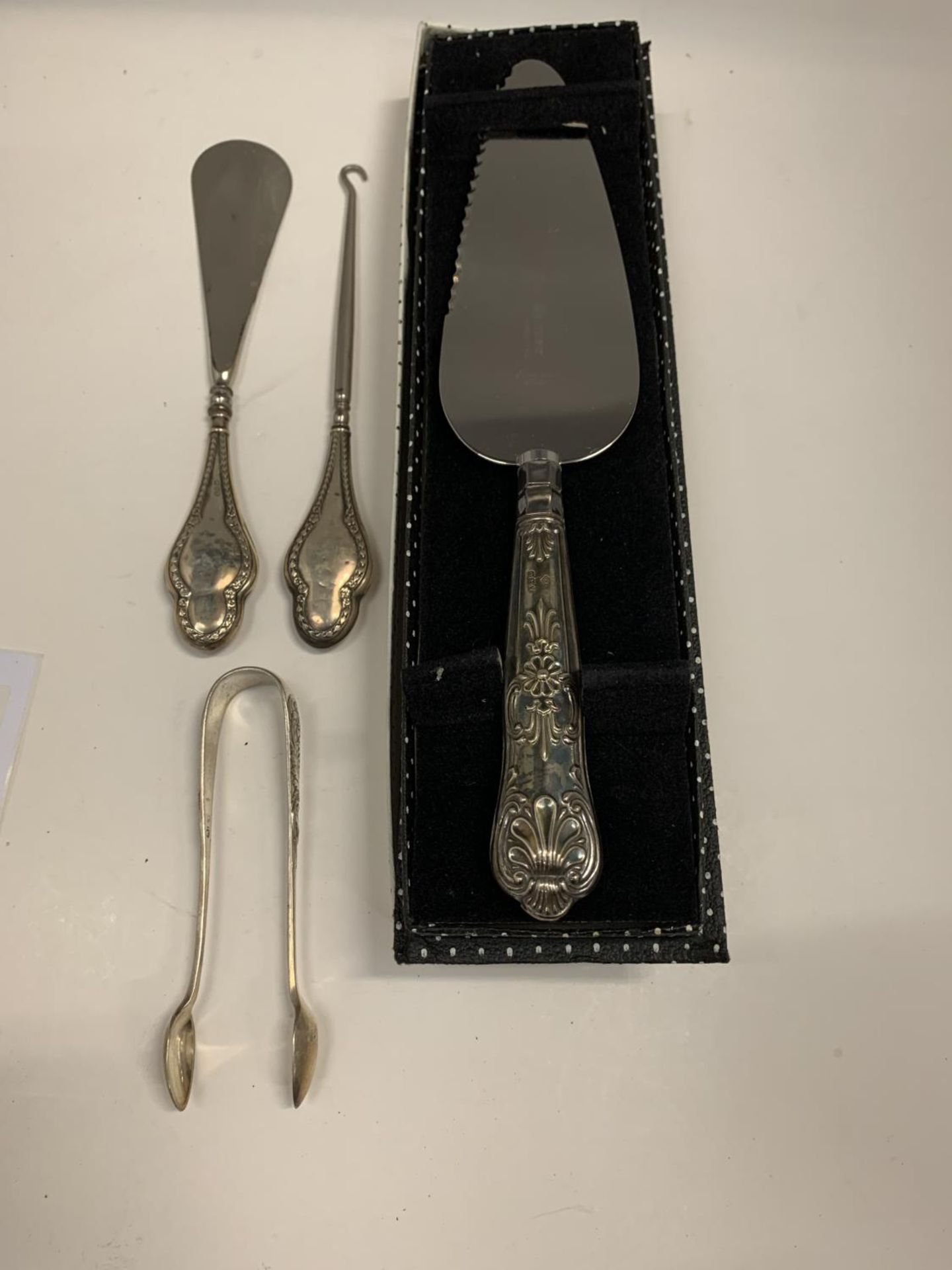 FOUR HALLMARKED ITEMS OF SILVER TO INCLUDE A HANDLED CAKE SLICE IN A BOX, A BUTTON HOOK AND SHOE