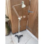 A VINTAGE ANGLE POISE LAMP ON A CAST IRON TRIPOD BASE WITH CASTERS