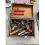 A VINTAGE WOODEN STORAGE CHEST CONTAINING AN ASSORTMENT OF TOOLS TO INCLUDE BRACE DRILL, HAMMERS AND