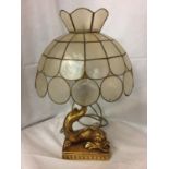 AN ORNATE GILDED LAMP BASE DEPICTING A FISH WITH A CAPIZ SHELL LAMP SHADE