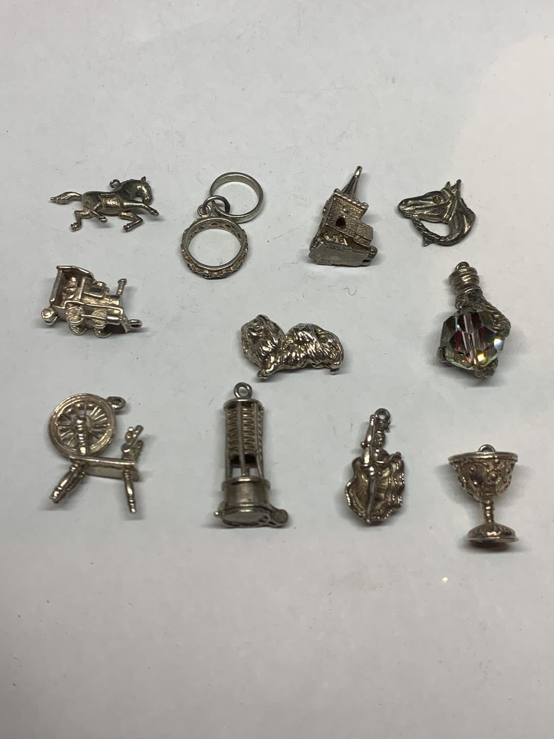 ELEVEN VARIOUS SILVER CHARMS TO INCLUDE HORSES, MOULIN ROUGE DANCER, DOG, TRAIN CHURCH ETC