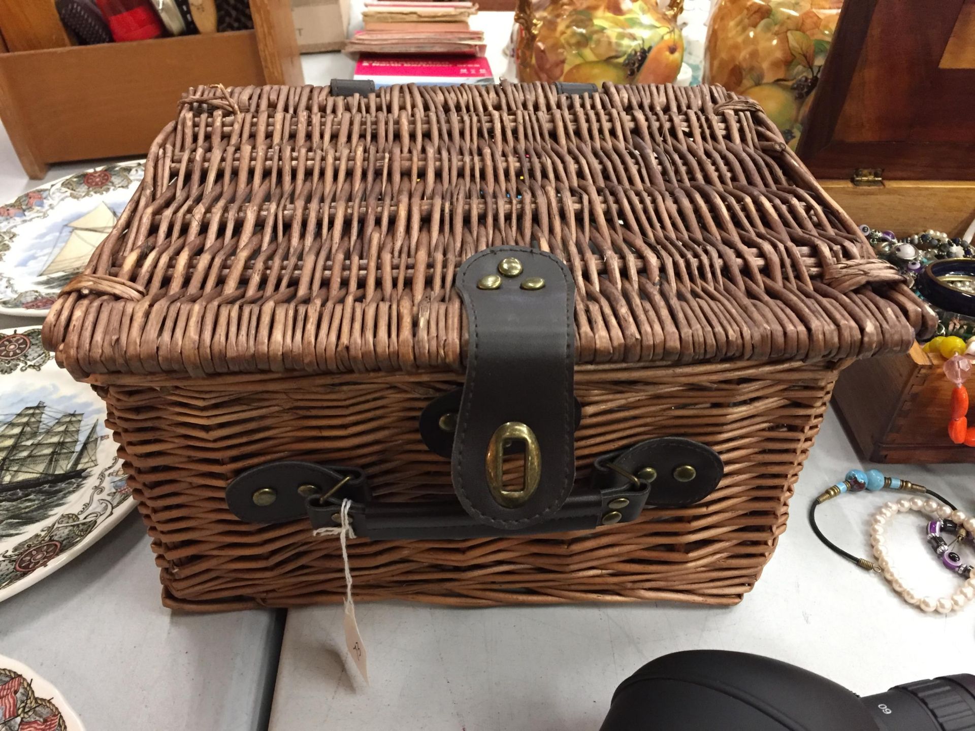 A WICKER PICNIC BASKET WITH PLATES, BOWLS AND CUPS