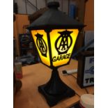 A CAST METAL LAMP WITH AA GARAGE THREE SIDED DETAIL TO PANELS AND BELIEVED IN WORKING ORDER BUT NO