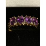 A 9 CARAT GOLD RING WITH FOUR IN LINE PURPLE STONES SIZE P GROSS WEIGHT 2.1 GRAMS