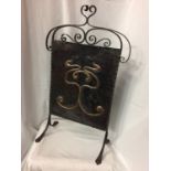 AN ARTS AND CRAFTS FIRE SCREEN WITH A DECORATIVE COPPER PANEL ON A WROUGHT IRON FRAME