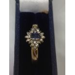 A 9 CARAT GOLD RING WITH A LIGHT BLUE STONE AND DIAMONDS IN A CLUSTER DESIGN SIZE L/M WITH A