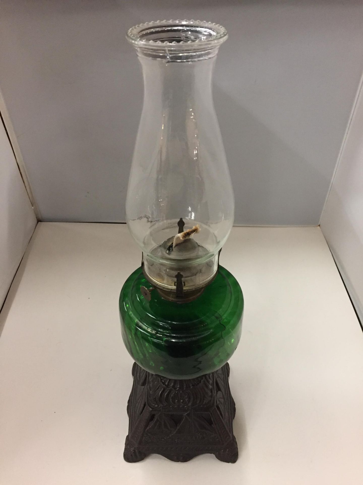 A CAST BASED OIL LAMP WITH A GREEN GLASS BODY AND CLEAR GLASS CHIMNEY