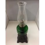 A CAST BASED OIL LAMP WITH A GREEN GLASS BODY AND CLEAR GLASS CHIMNEY