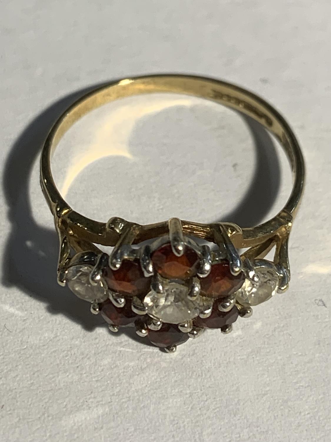 A 9 CARAT GOLD RING WITH THREE CLEAR STONES AND SIX RED STONES IN A FLOWER DESIGN SIZE Q GROSS - Image 2 of 3
