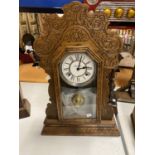 A VINTAGE GINGERBREAD CLOCK IN A CARVED WOODEN CASE WITH FRONT OPENING