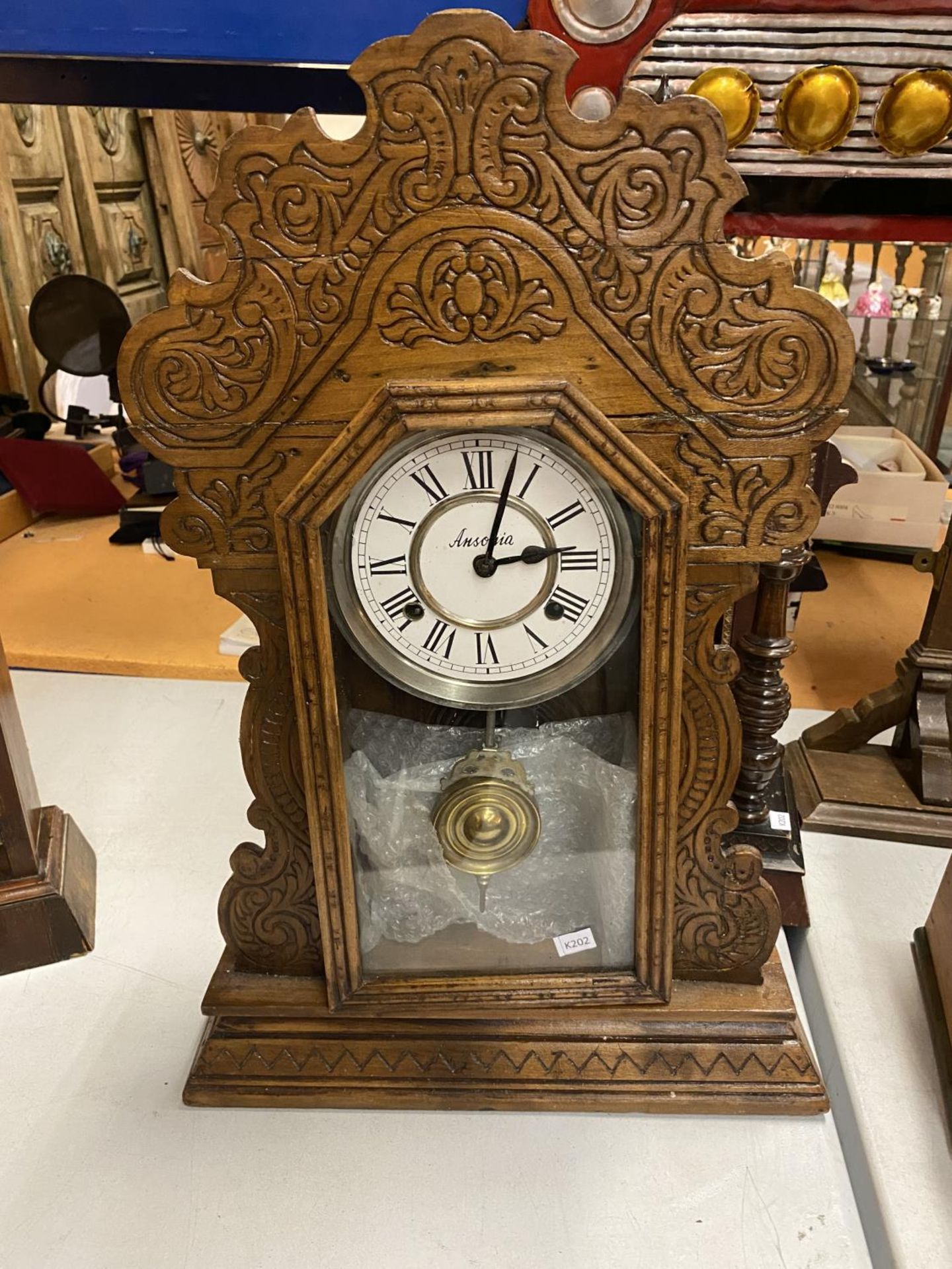 A VINTAGE GINGERBREAD CLOCK IN A CARVED WOODEN CASE WITH FRONT OPENING