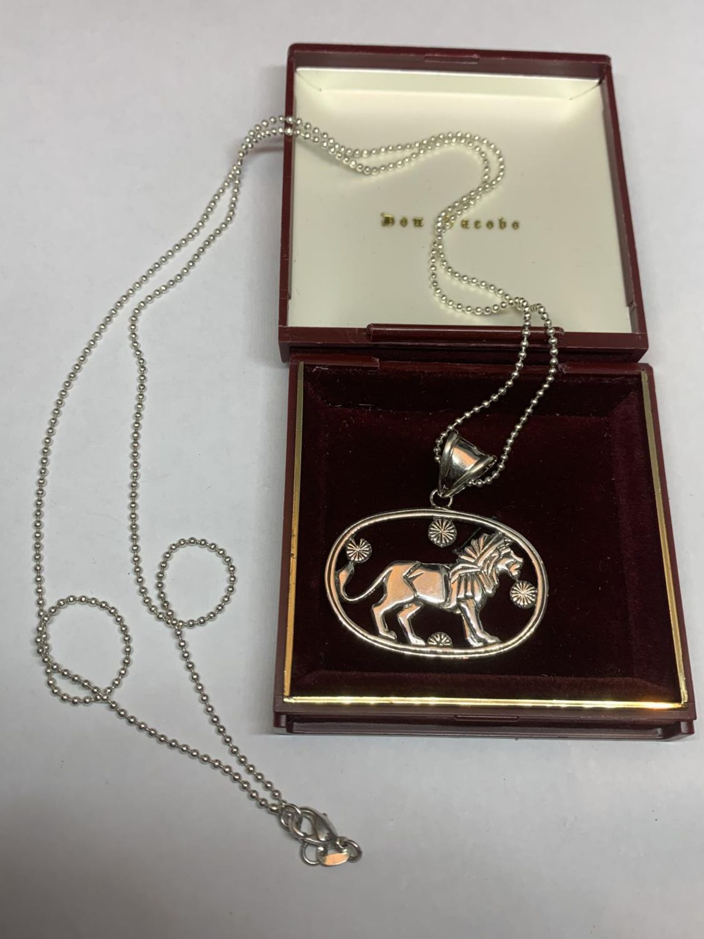 A SILVER NECKLACE WITH A LION PENDANT IN A PRESENTATION BOX