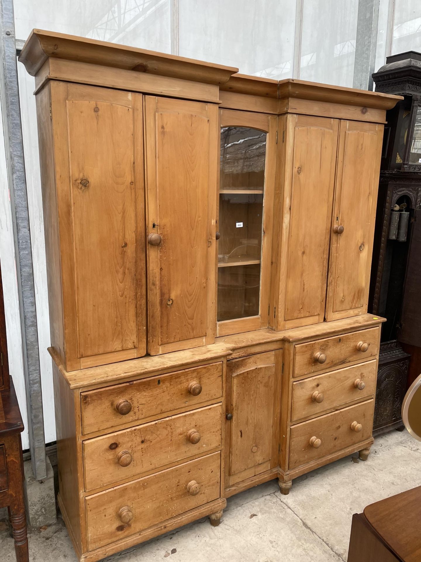 A VICTORIAN PINE INVERTED BREAKFRONT HOUSEKEEPERS CUPBOARD WITH SIX DRAWERS AND CUPBOARD TO THE