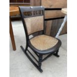 AN EBONISED EDWARDIAN ROCKING CHAIR WITH CANE SEAT AND BACK