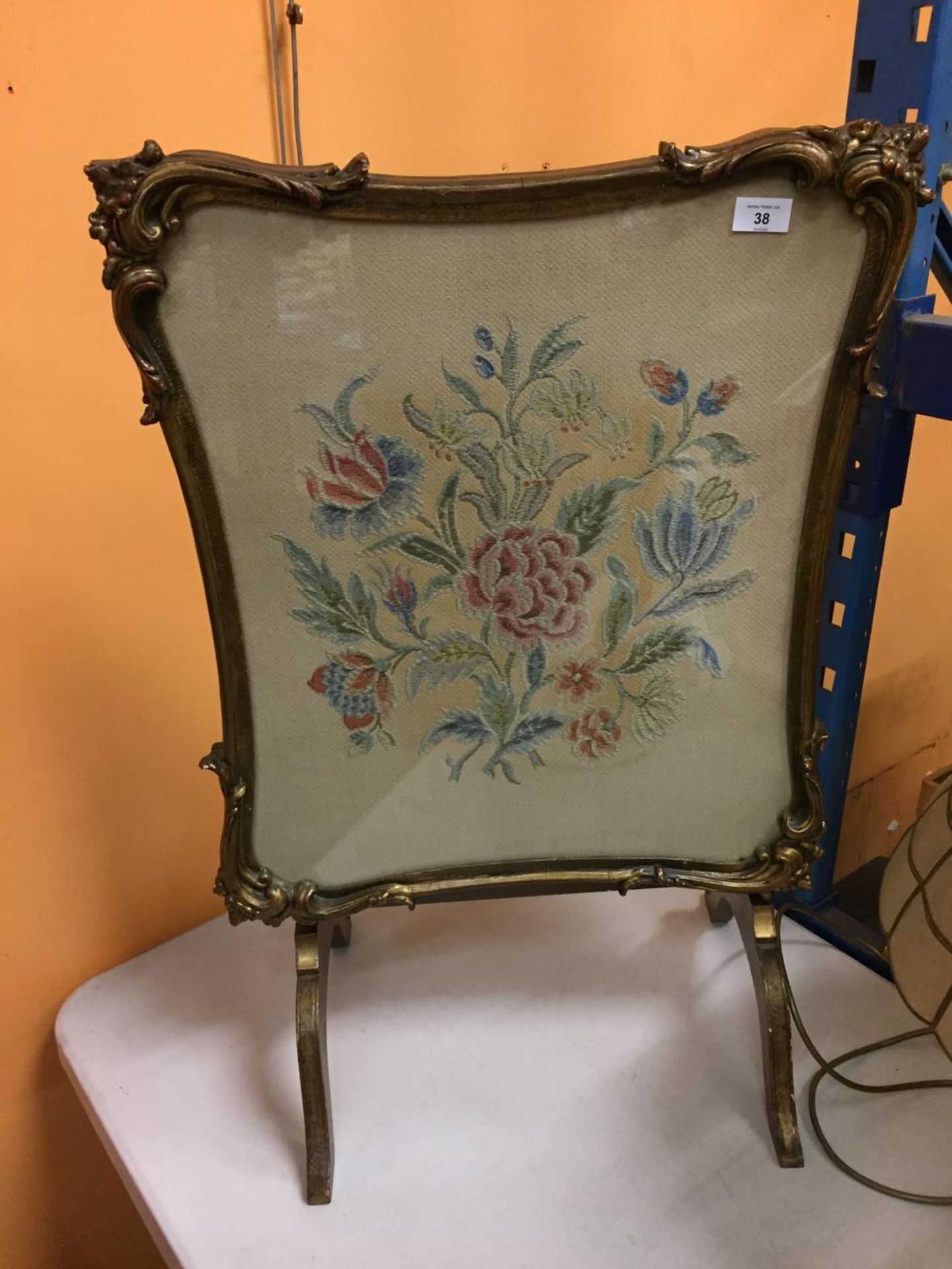 AN ORNATELY FRAMED CROSS STITCHED FIRE SCREEN WITH A FLOWER DESIGN