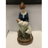 A TALL FIGURINE OF A LADY HOLDING A BABY WITH A SHEEP
