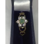 A 9 CARAT GOLD RING WITH GREEN AND CLEAR STONES IN A FLOWER STYLE SETTING WITH HEART DESIGN