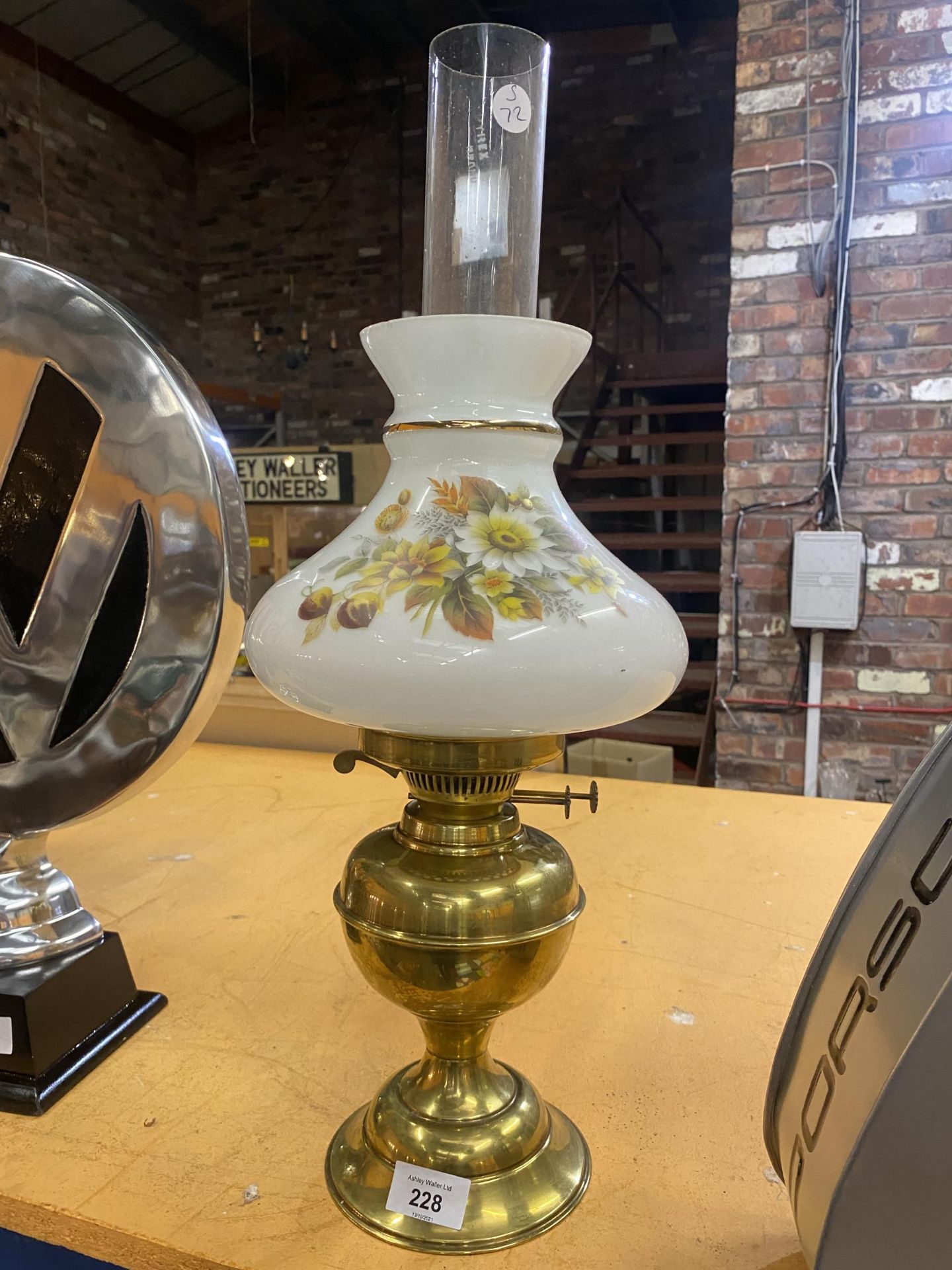 A BRASS BASED OIL LAMP WITH A CLEAR GLASS CHIMNEY AND A FLORAL GLASS SHADE