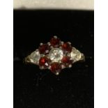 A 9 CARAT GOLD RING WITH THREE CLEAR STONES AND SIX RED STONES IN A FLOWER DESIGN SIZE Q GROSS