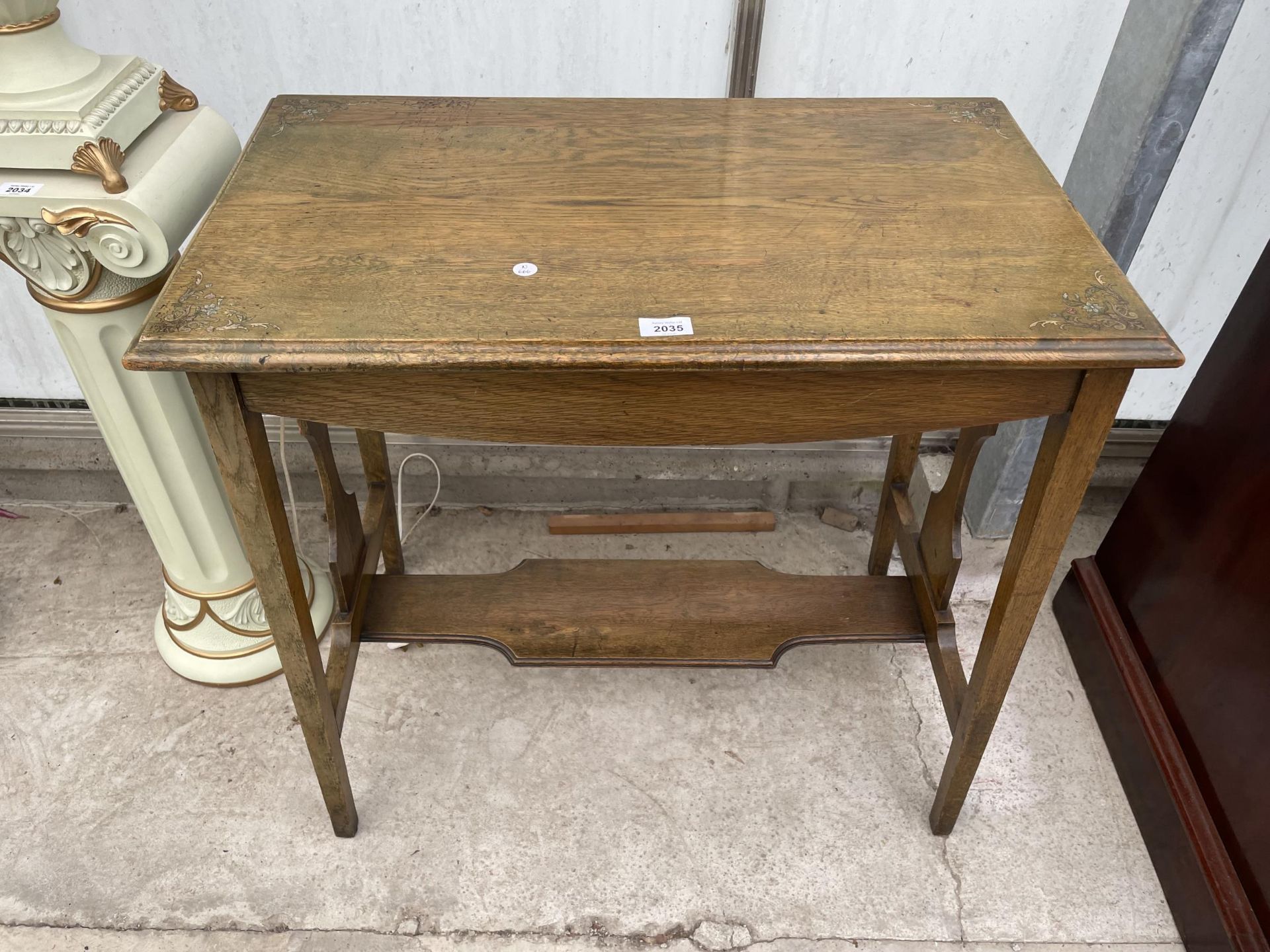 AN EARLY 20TH CENTURY OAK TWO TIER CENTRE TABLE WITH PAINTED FLORAL DECORATION TO THE TOP