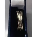 A 9 CARAT GOLD WHITE GOLD RING ON A TWIST WITH TEN IN LINE DIAMONDS SIZE O/P IN A PRESENTATION BOX
