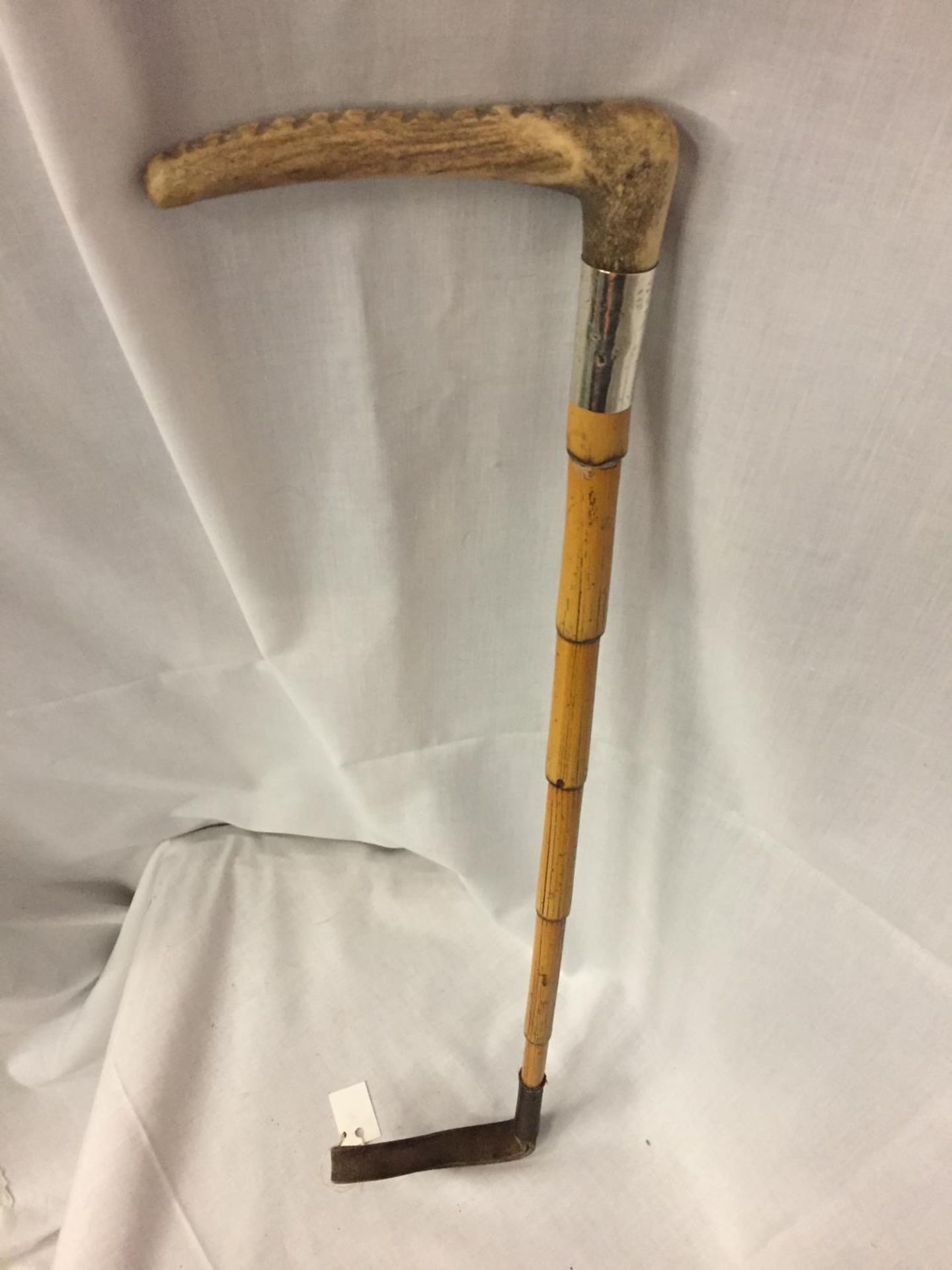A BAMBOO RIDING CROP WITH HORN HANDLE AND A SILVER COLLAR (INDISTINCT HALLMARK)