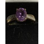 A 9 CARAT RING WITH A PURPLE CENTRE STONE AND POSSIBLY DIAMOND CHIPS TO THE SHOULDER SIZE P GROSS