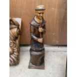 A TREEN CARVED FIGURE OF A MALE STIRING A PAN OVER A FIRE