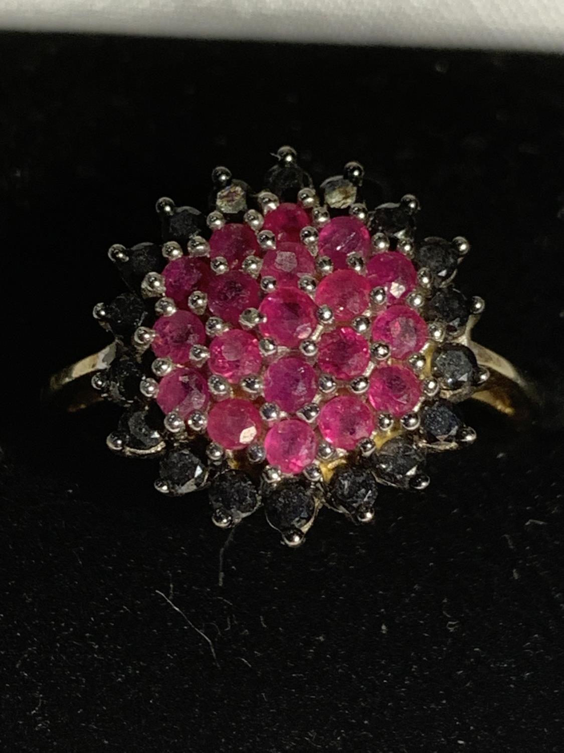 A 9 CARAT GOLD RING WITH A RED STONE CLUSTER SURROUNDED BY BLUE STONES SIZE P GROSS WEIGHT 4 GRAMS