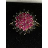 A 9 CARAT GOLD RING WITH A RED STONE CLUSTER SURROUNDED BY BLUE STONES SIZE P GROSS WEIGHT 4 GRAMS
