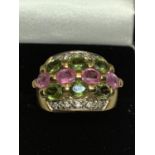 A 9 CARAT GOLD RING WITH GREEN AND PINK STONES AND CLEAR STONE CHIPS GROSS WEIGHT 7.6 GRAMS