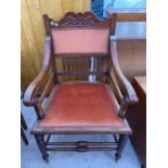 AN EDWARDIAN MAHOGANY ELBOW CHAIR ON TURNED LEGS AND STRETCHERS WITH CARVED TOP RAIL
