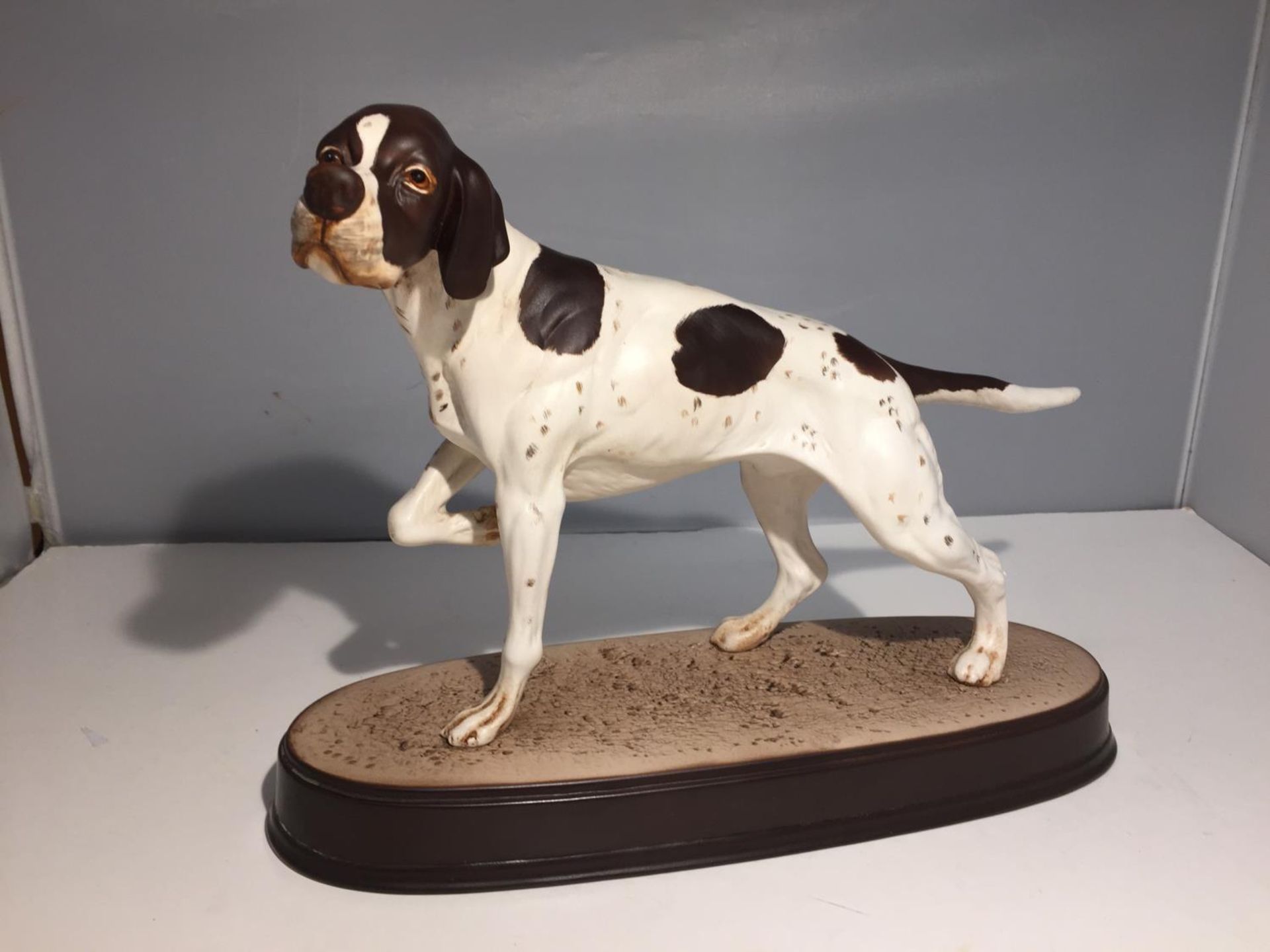 A BESWICK POINTER ON A CERAMIC PLINTH